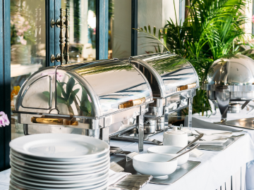 Buffet de desayuno de hotel con frutas frescas, bollería, cereales, café y zumos, presentado de forma ordenada y atractiva.